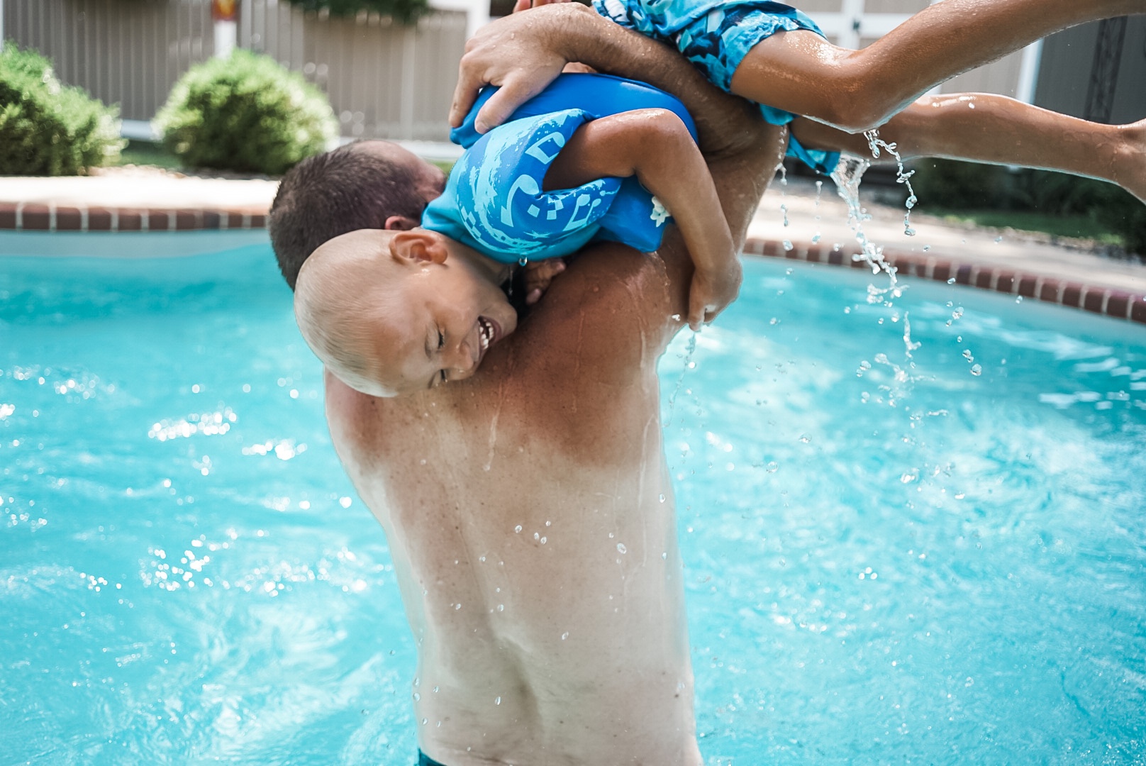 Man holding laughing boy in swimming pool. 