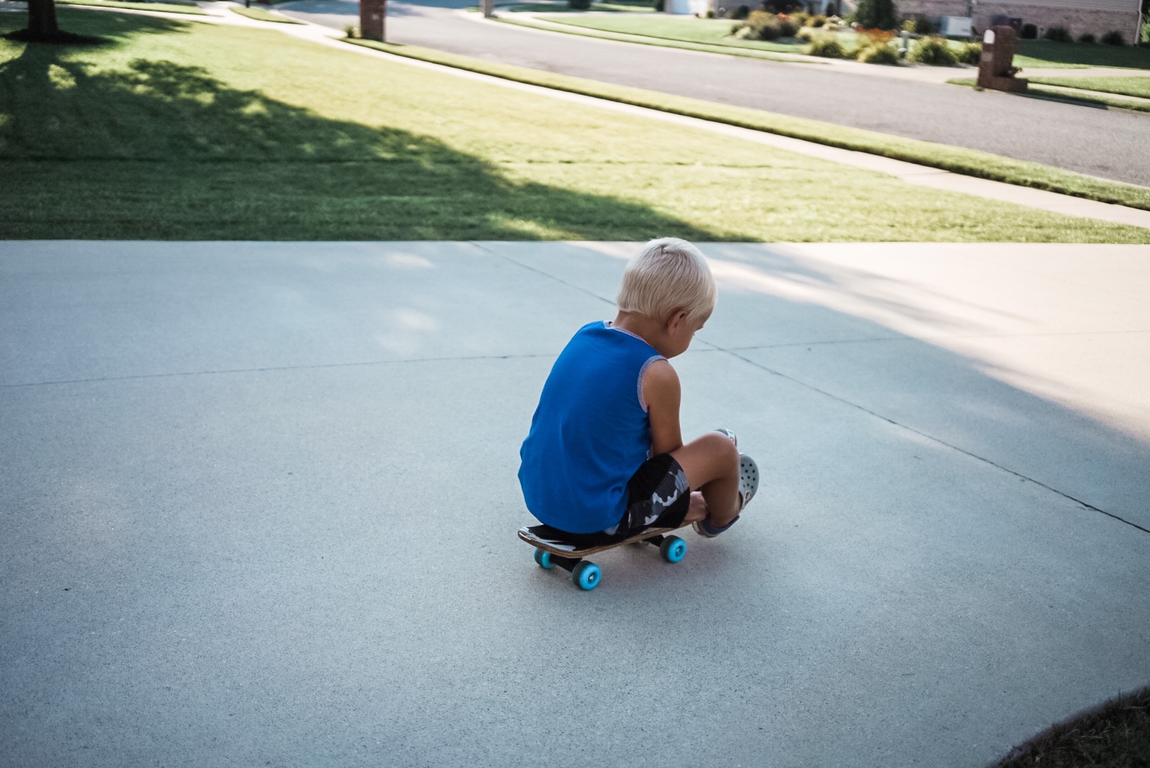 Boy on sitting on a skate board rolling down a hill