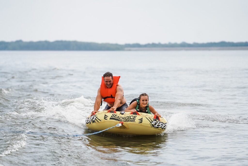 One adult man and teenage girl on a boat tube 